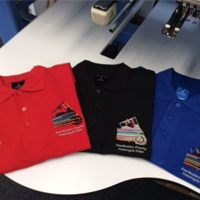 A selection of polo shirts with embroidered logos attached to them.